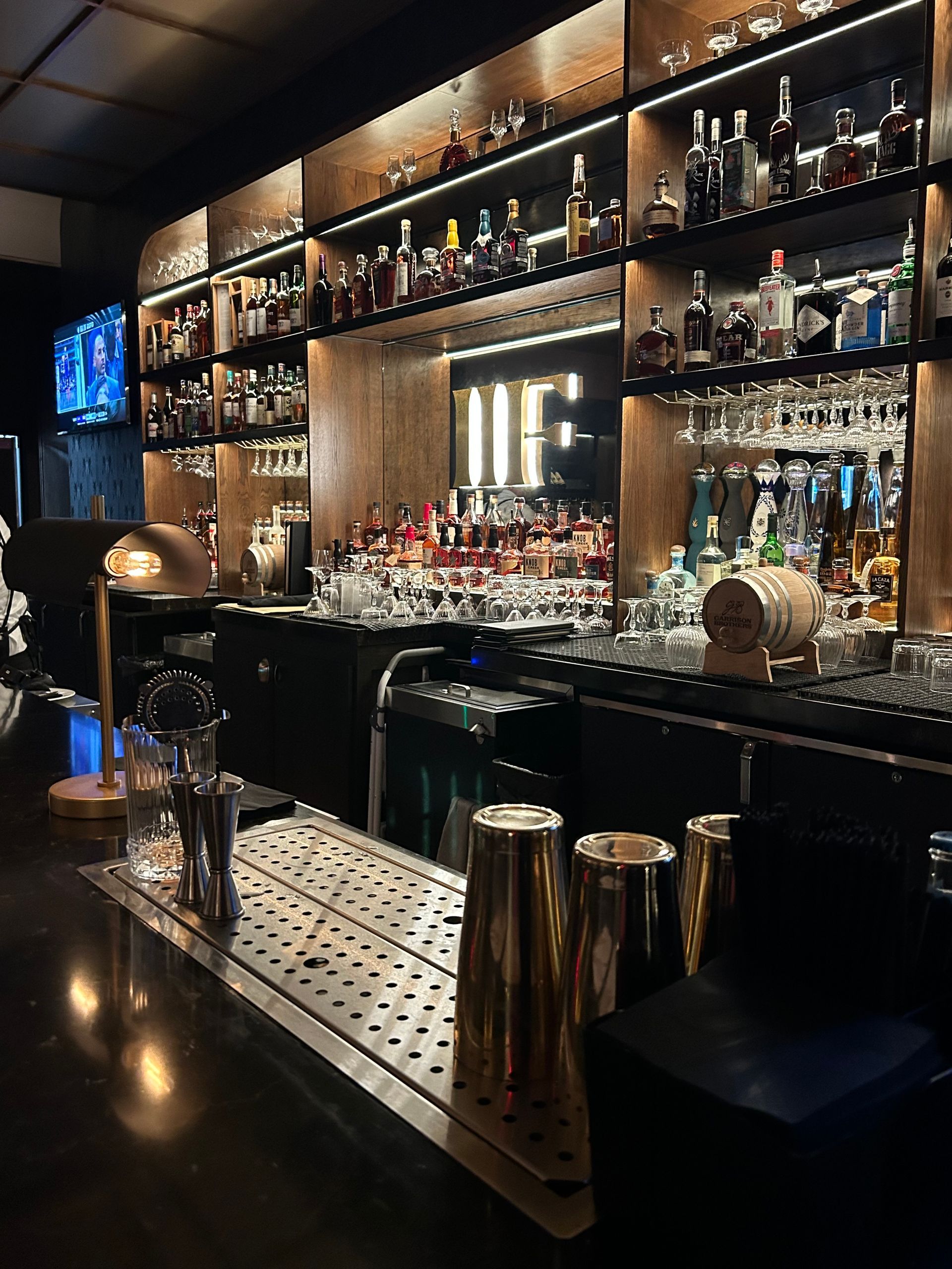 A bar with a lot of bottles and glasses on the shelves.