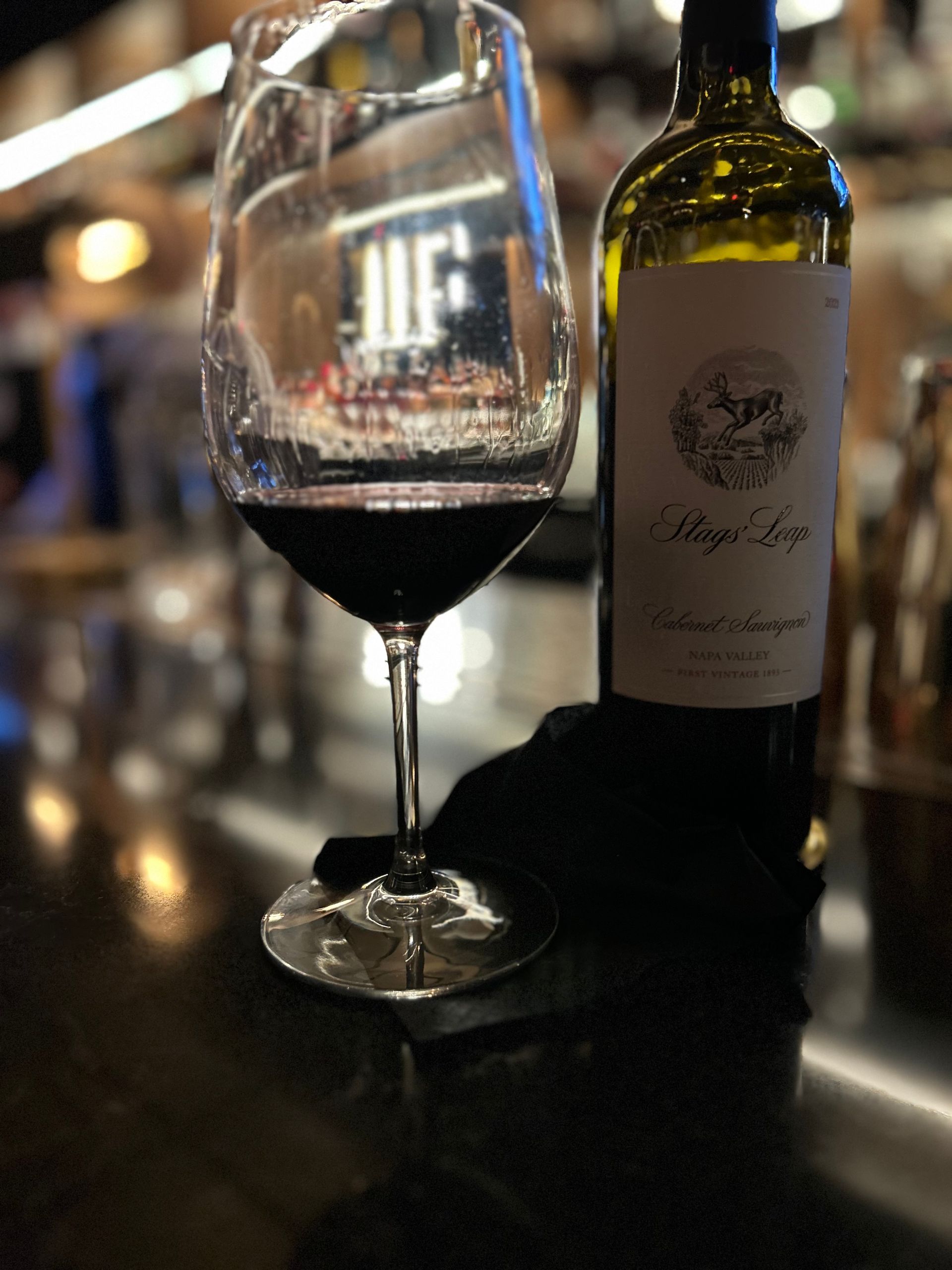 A bottle of wine sits next to a glass of wine