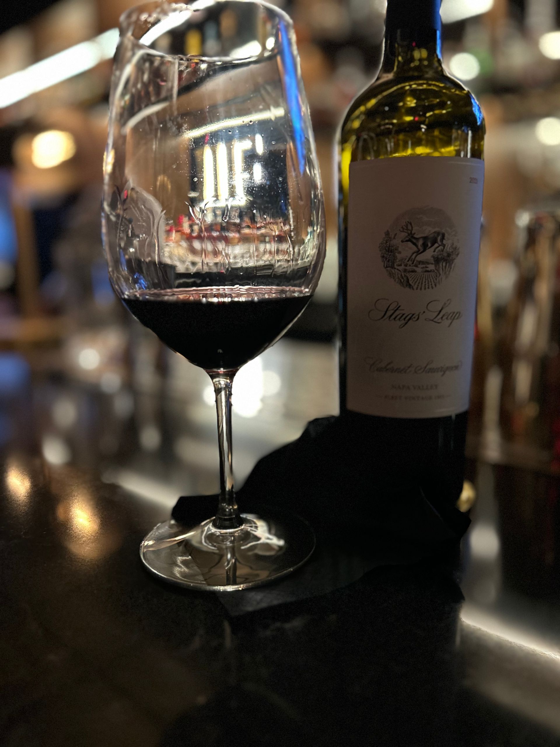 A bottle of wine sits next to a glass of wine
