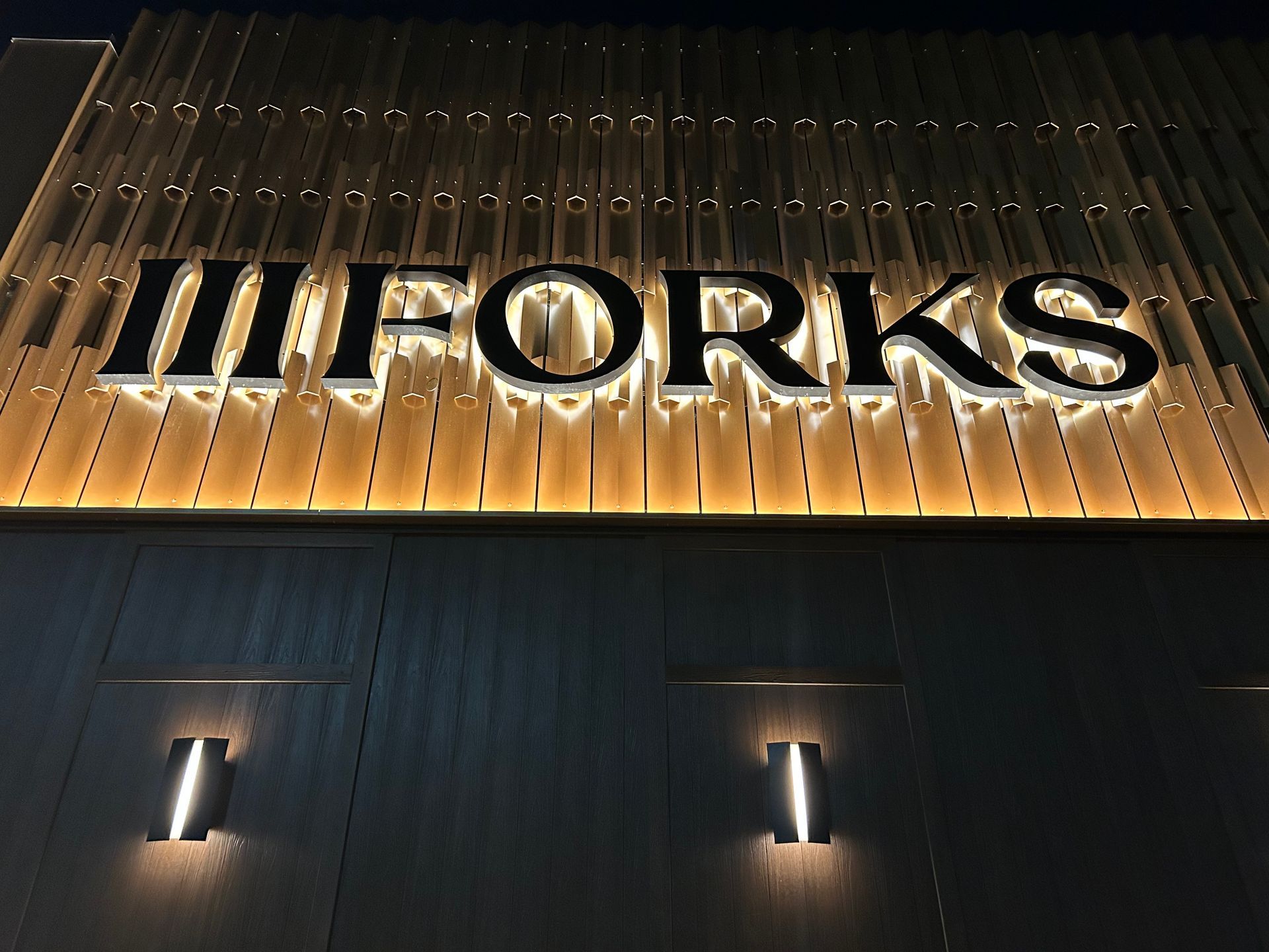 A sign that says ii forks is lit up at night