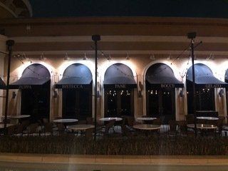 A restaurant with tables and chairs outside at night