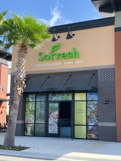 The front of a sofresh store with a palm tree in front of it