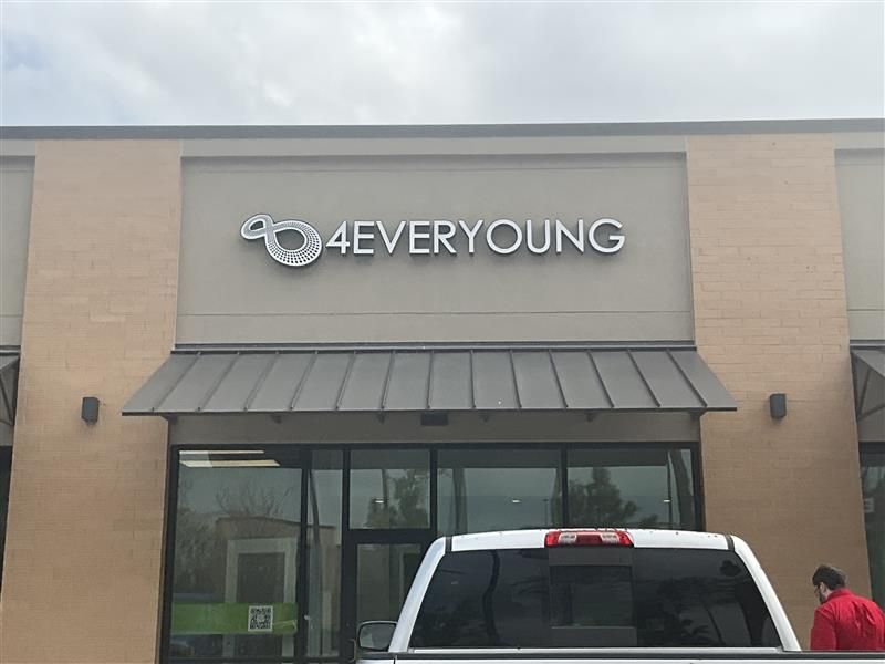 A white truck is parked in front of a 4everyoung store