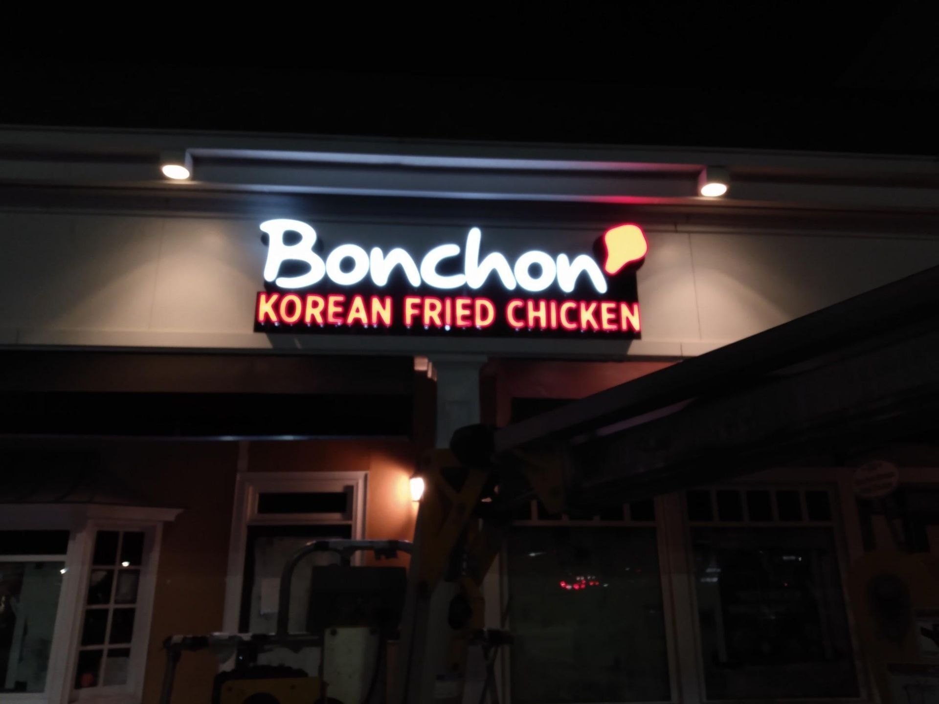 A sign for bonchon korean fried chicken is lit up at night