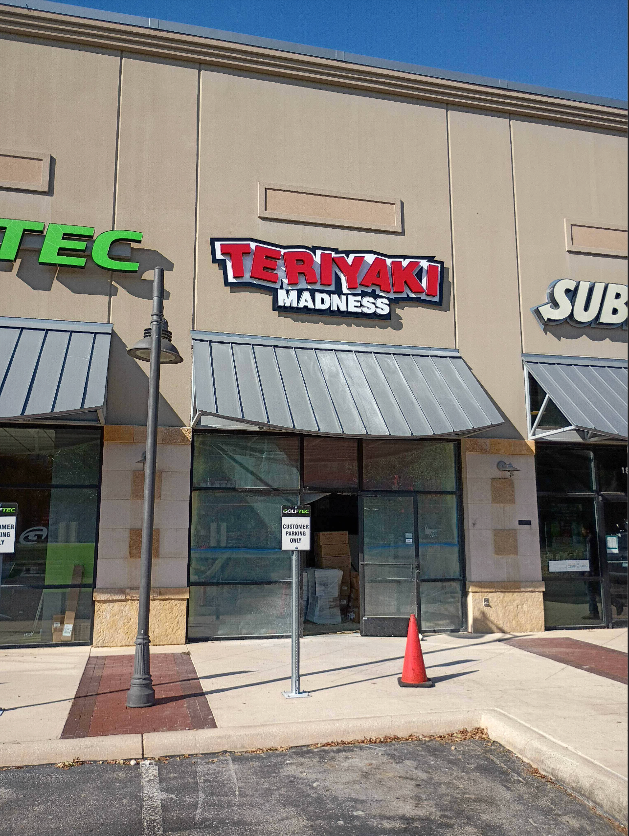 Teriyaki Madness restaurant storefront with closed entrance. Red and white sign, beige building.