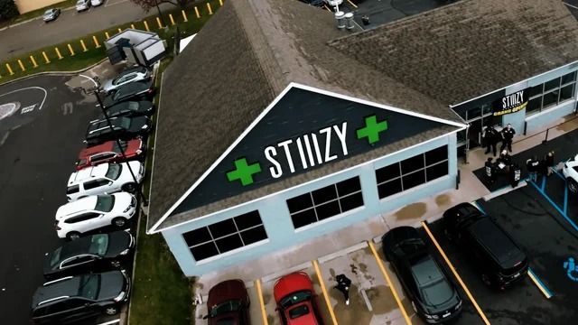 An aerial view of a store called stiizy with cars parked in front of it.