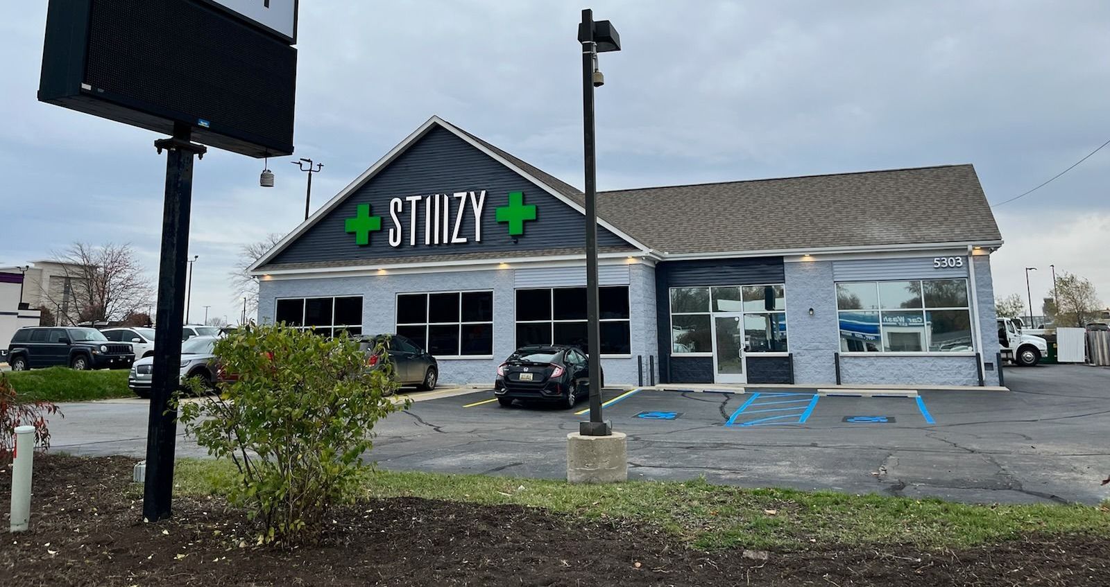 A store front with a sign in front of it and a car parked in front of it.