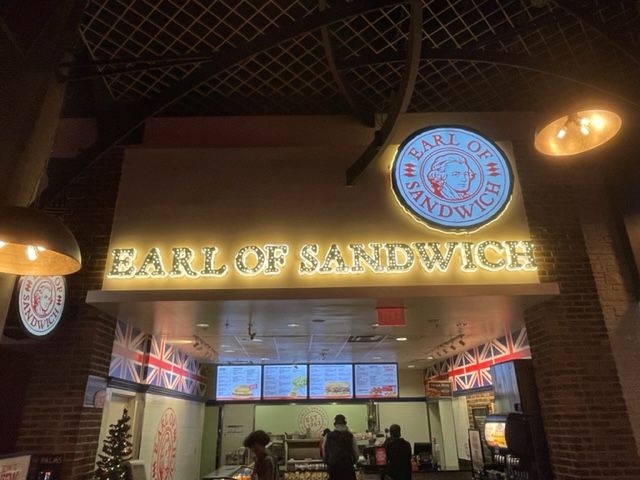 A restaurant called earl of sandwich is lit up at night