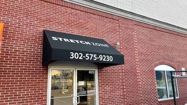 A brick building with a black awning over the door.