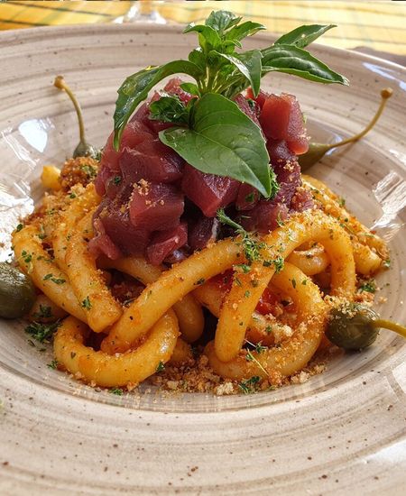 Un primo piano di un piatto di pasta con carne e verdure su un tavolo.