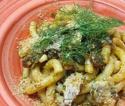Un primo piano di un piatto di pasta con aneto sopra.