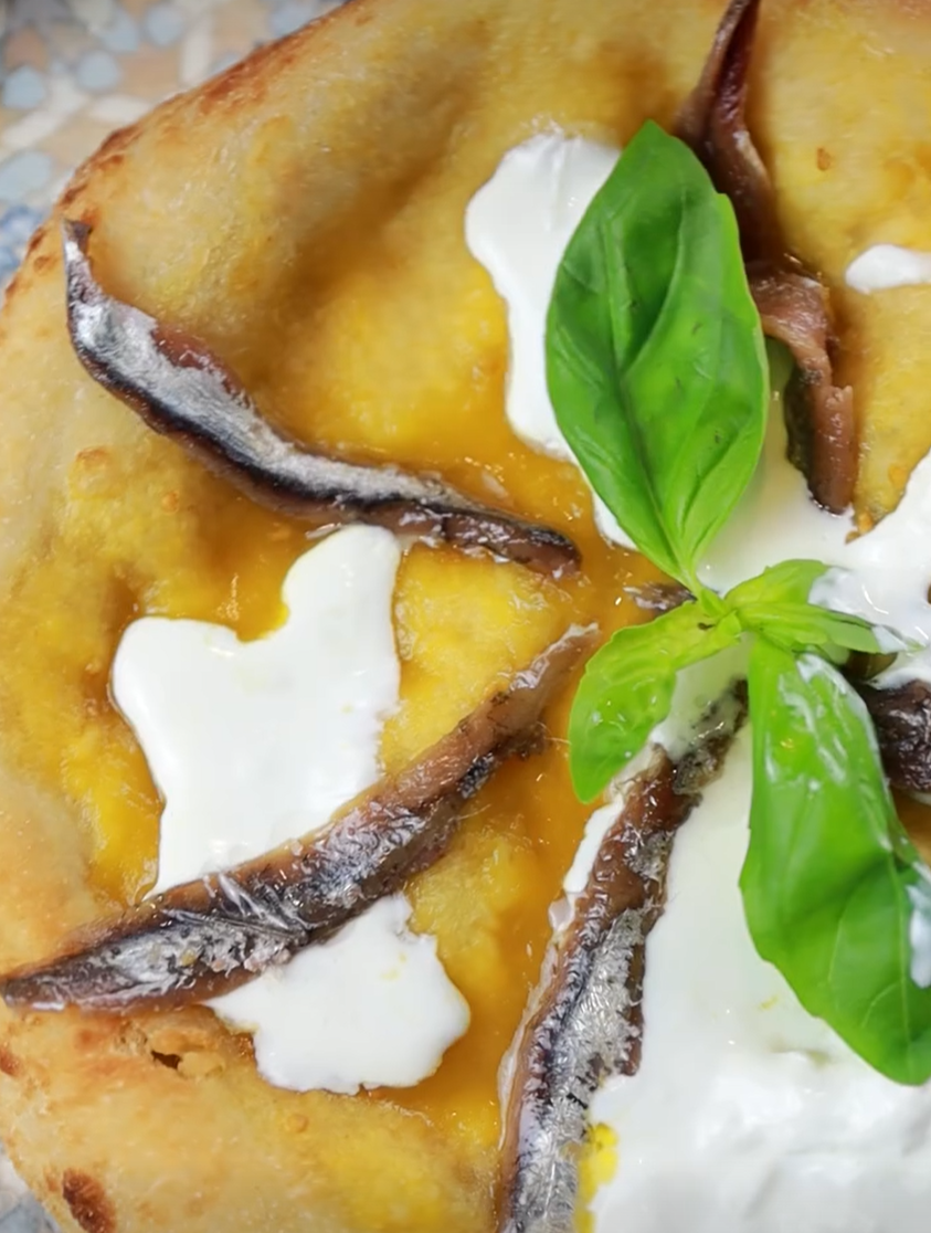 Una pizza con sopra acciughe e basilico