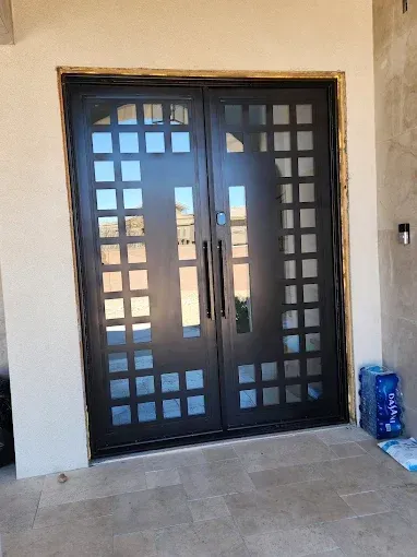 Black double front door with square glass panels and beige entryway wall.