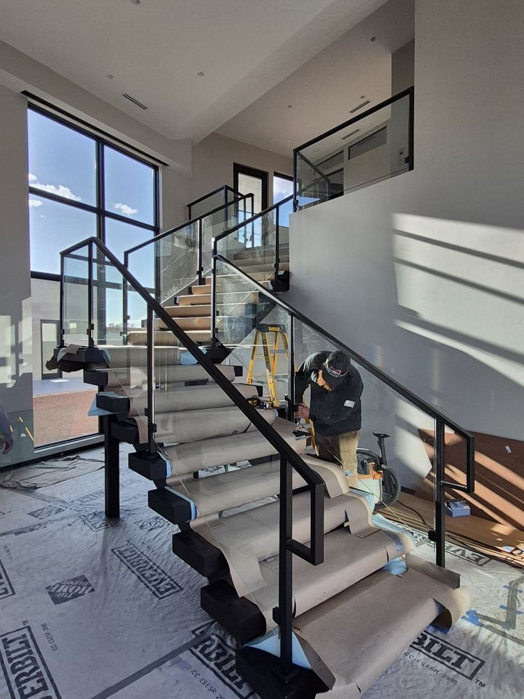 Workers installing carpet on a modern staircase in a bright, unfinished house