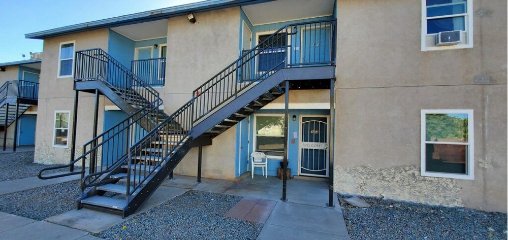 Exterior of beige apartment building with black metal stairs and blue railings