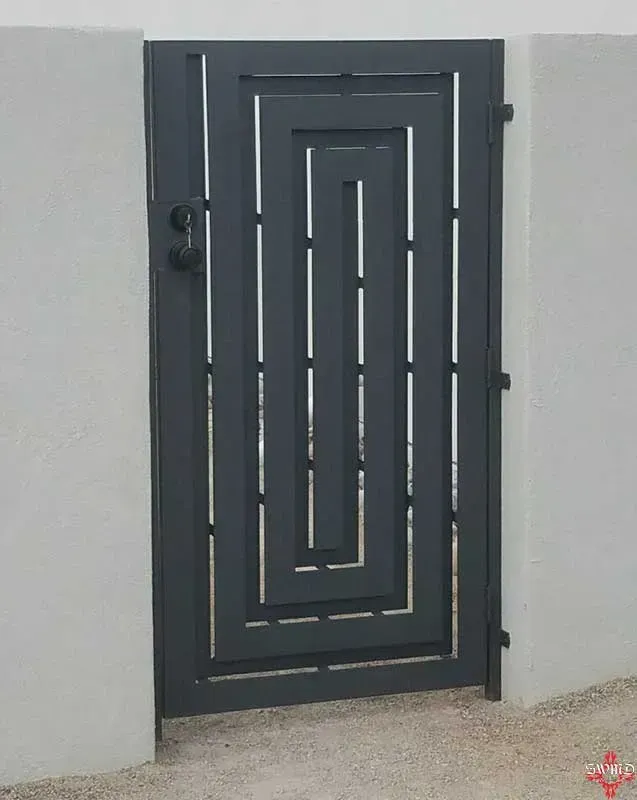 Dark gray metal security door with geometric design set in a light gray wall.