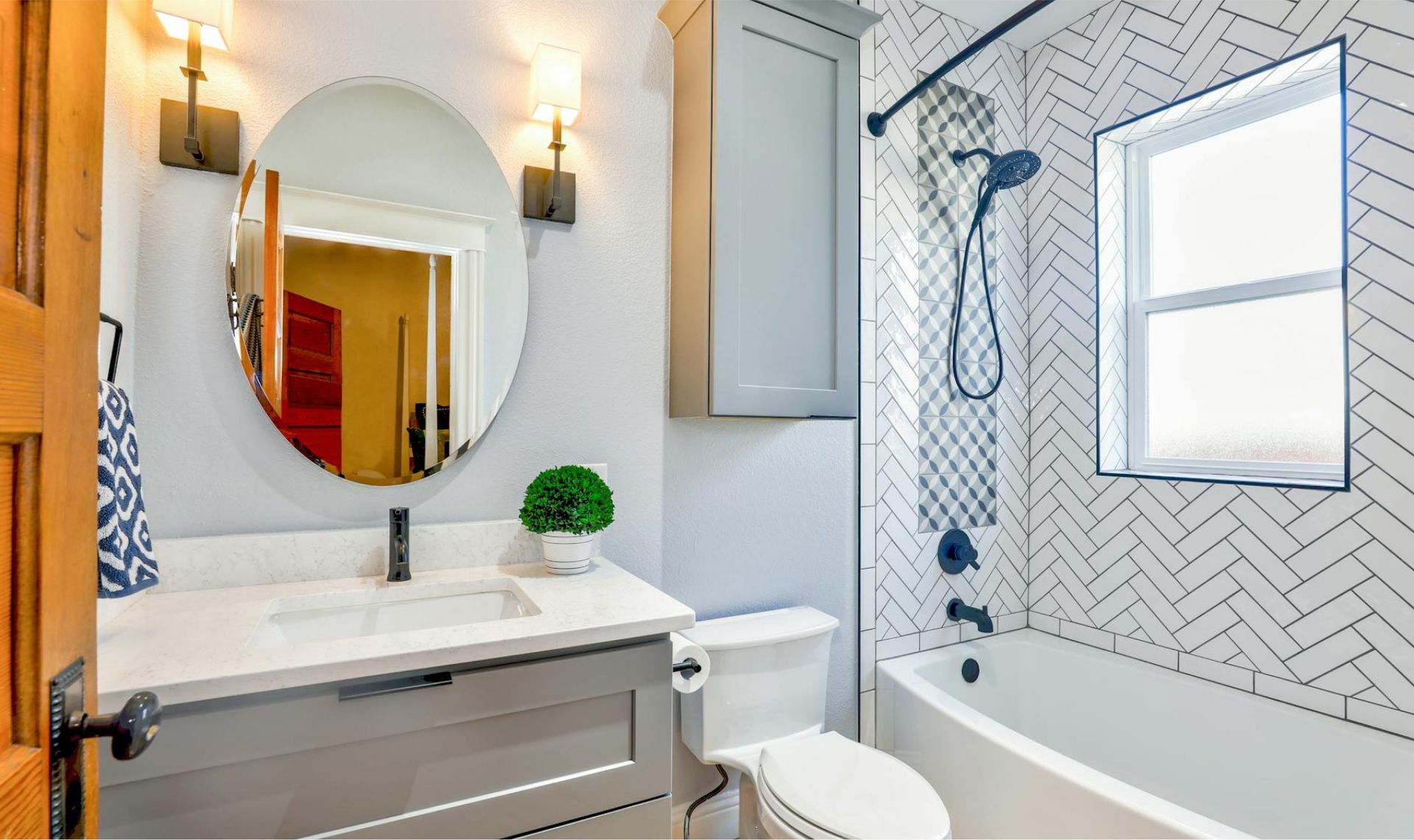 Modern bathroom interior featuring a round mirror, gray cabinetry, and a white bathtub, highlighting cleanliness and organization, relevant to Life Maid Easy's deep cleaning services.
