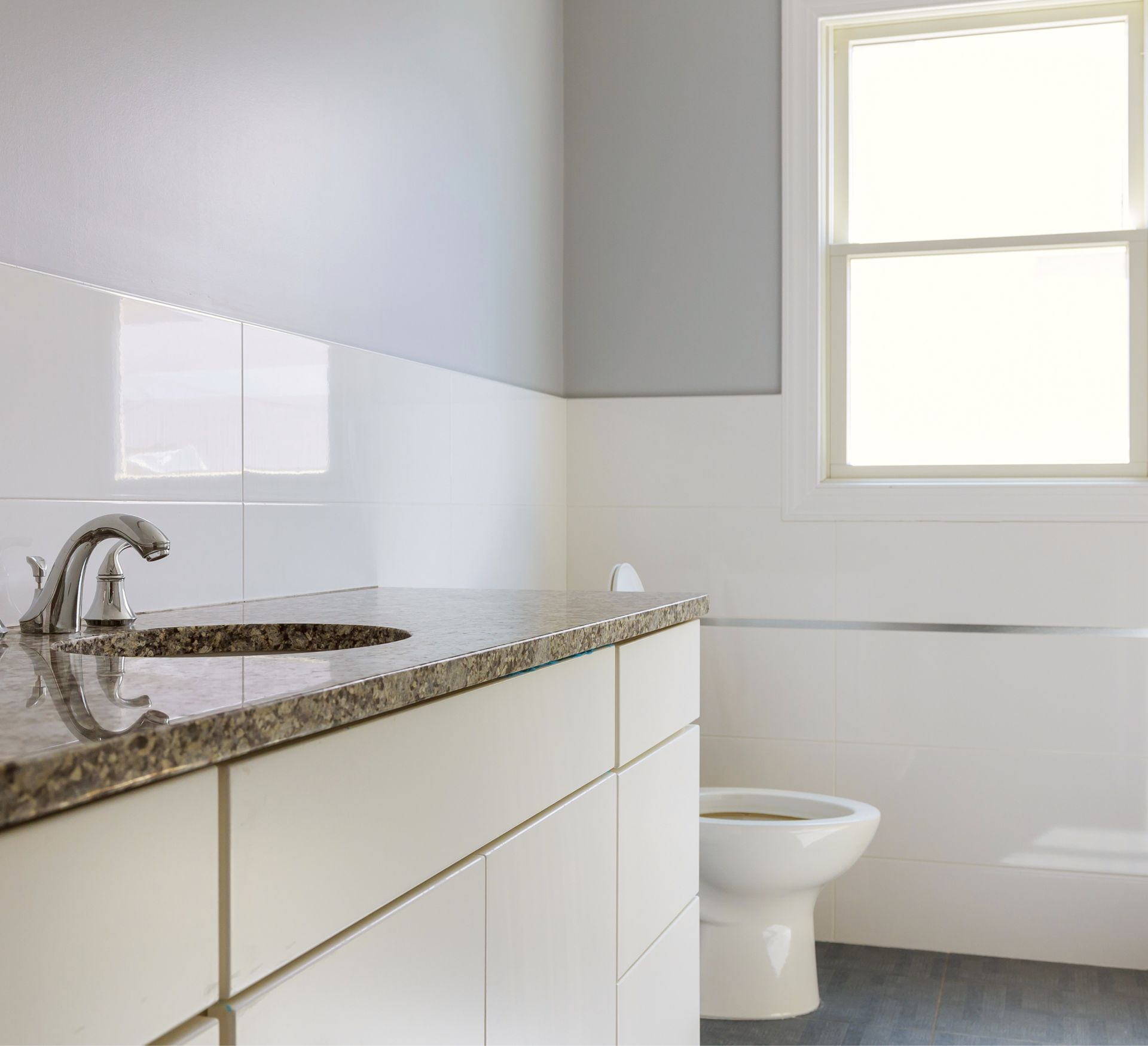 Modern bathroom interior featuring a countertop with a sink and faucet, white cabinetry, and a toilet, emphasizing cleanliness and organization for move-in or move-out services.
