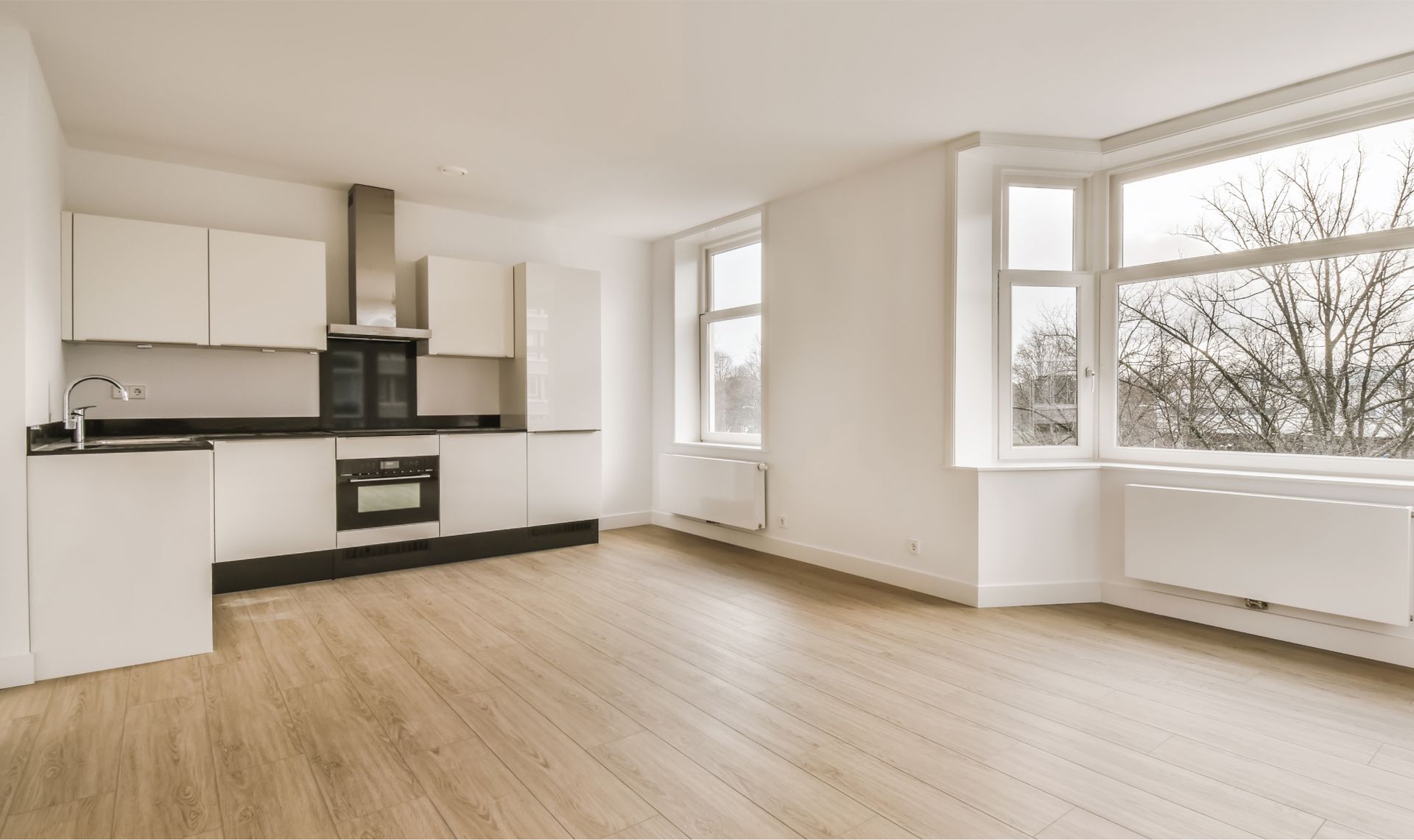 Modern kitchen interior with white cabinetry, black countertops, and large windows, showcasing a clean and spacious design ideal for move-in cleaning services by Life Maid Easy.