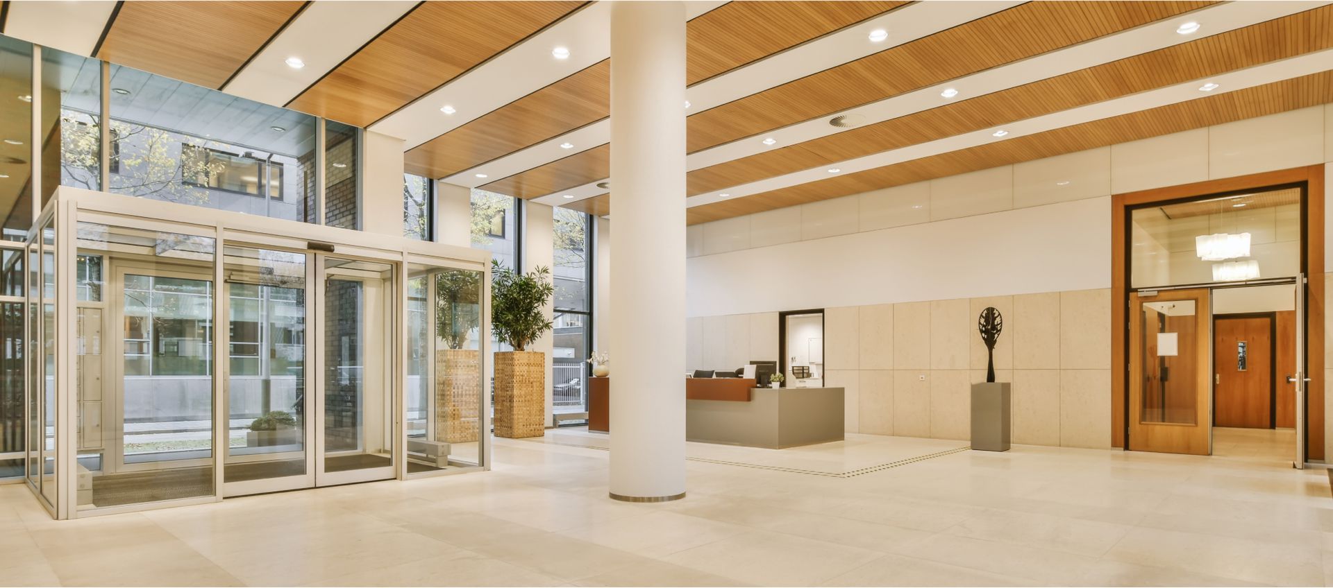 Modern office lobby with glass entrance, decorative plants, and reception desk, highlighting a clean and welcoming workspace for professional services.