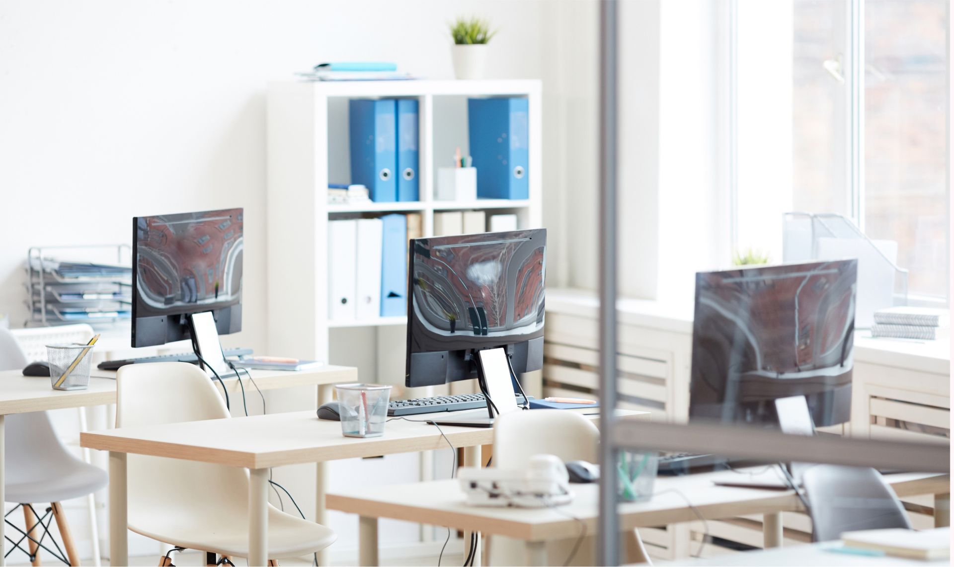 Modern office workspace with multiple computer desks, monitors, and organized shelves, reflecting a clean and professional environment for Life Maid Easy's office cleaning services.