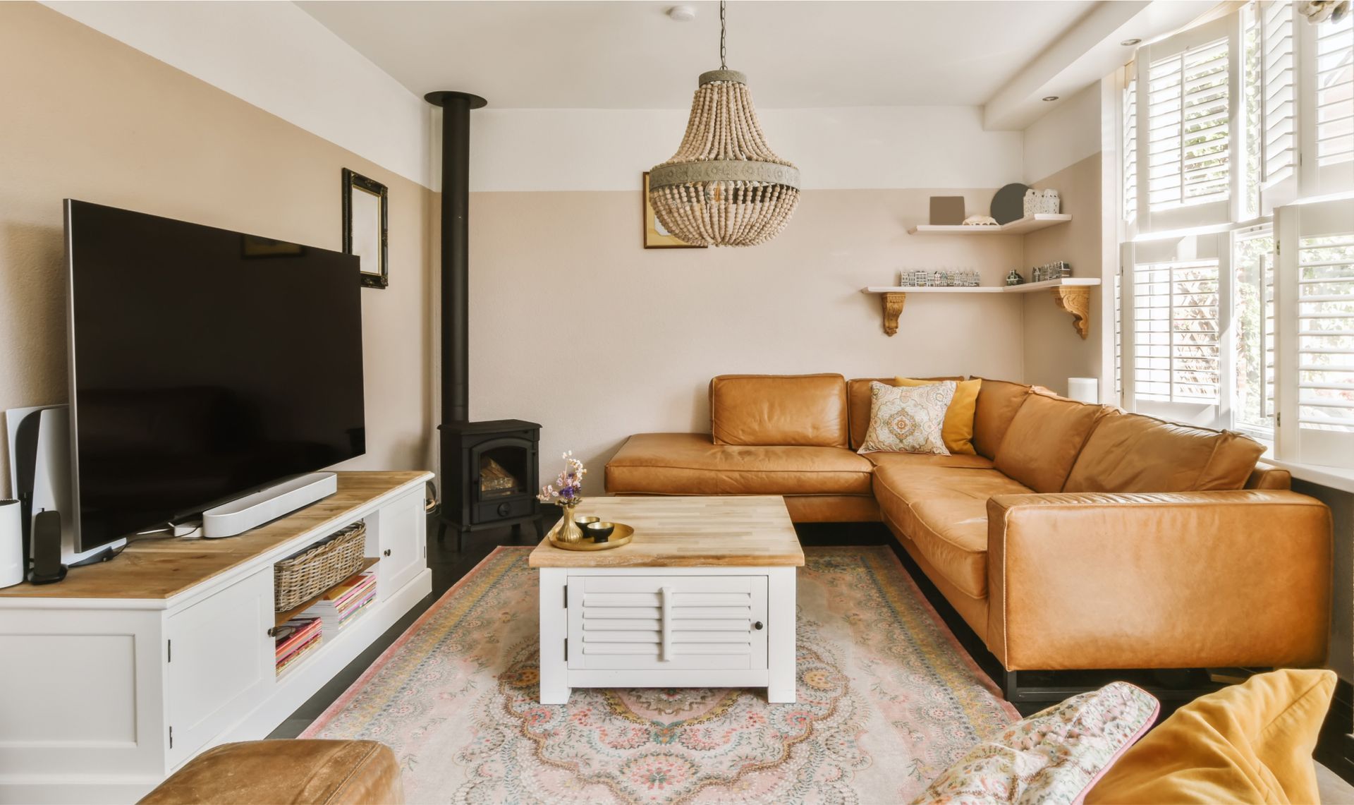 Cozy living room featuring a leather sectional sofa, flat-screen TV, decorative coffee table, and a stylish chandelier, emphasizing a clean and inviting space ideal for relaxation and comfort.