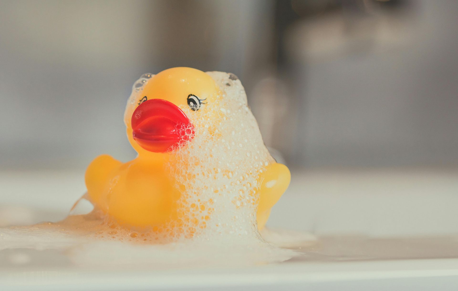 Rubber duck covered in bubbles, symbolizing toy cleaning and hygiene for children's toys in a home environment.