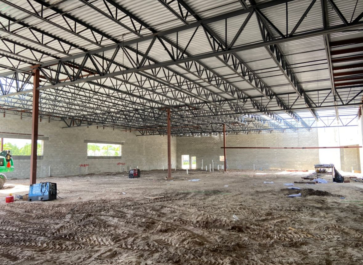 Construction site interior. Steel framework ceiling, dirt floor, unfinished walls, and support beams.