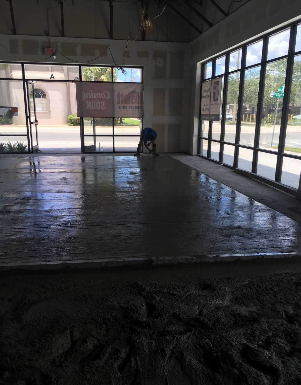 Man leveling wet concrete floor in a commercial building under construction.