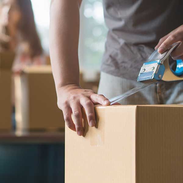 Close-up hand of man use tape sealing cardboard box.