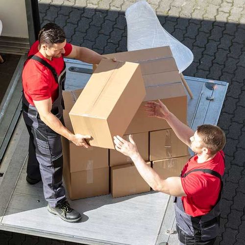 Male Movers Unloading The Cardboard Boxes Form Truck