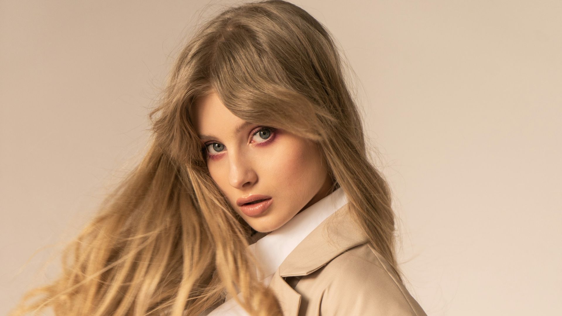 A woman with clear, even skin tone in warm studio light
