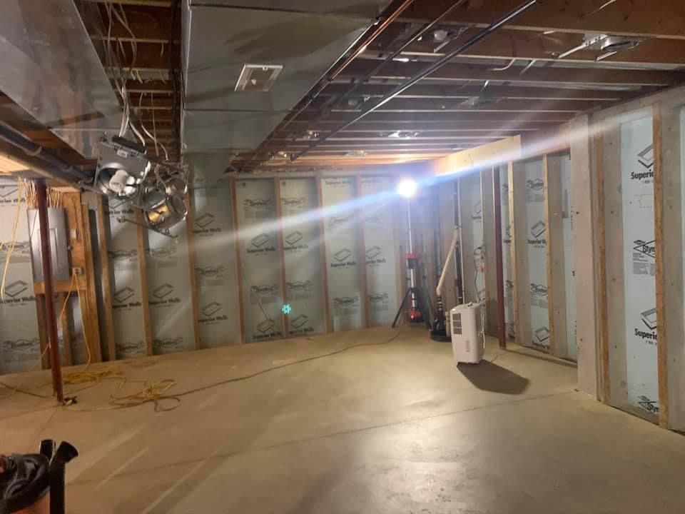 Basement under construction with exposed framing, insulation, concrete floor, and ductwork.
