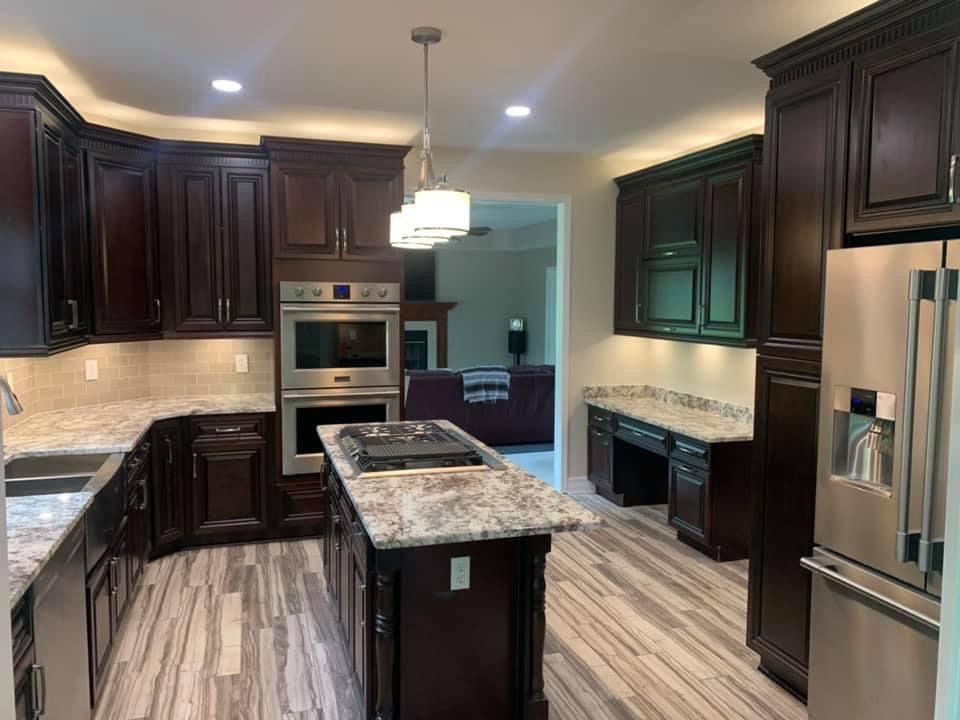 Dark wood kitchen with granite countertops, stainless steel appliances, and light wood-look floors.