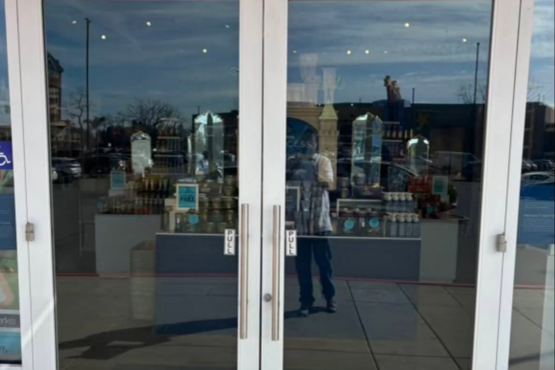 Glass storefront doors reflecting an outdoor plaza and the person taking the photo Glass storefront doors reflecting an outdoor plaza and the person taking the photo