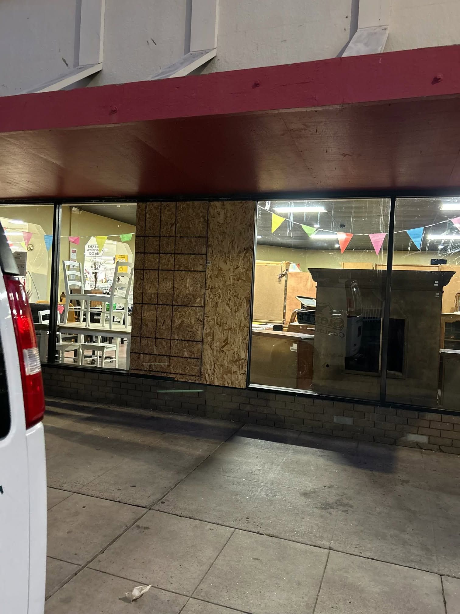 Storefront with large glass windows at dusk, lit interior, and a white van parked nearby Storefront with large glass windows at dusk, lit interior, and a white van parked nearby