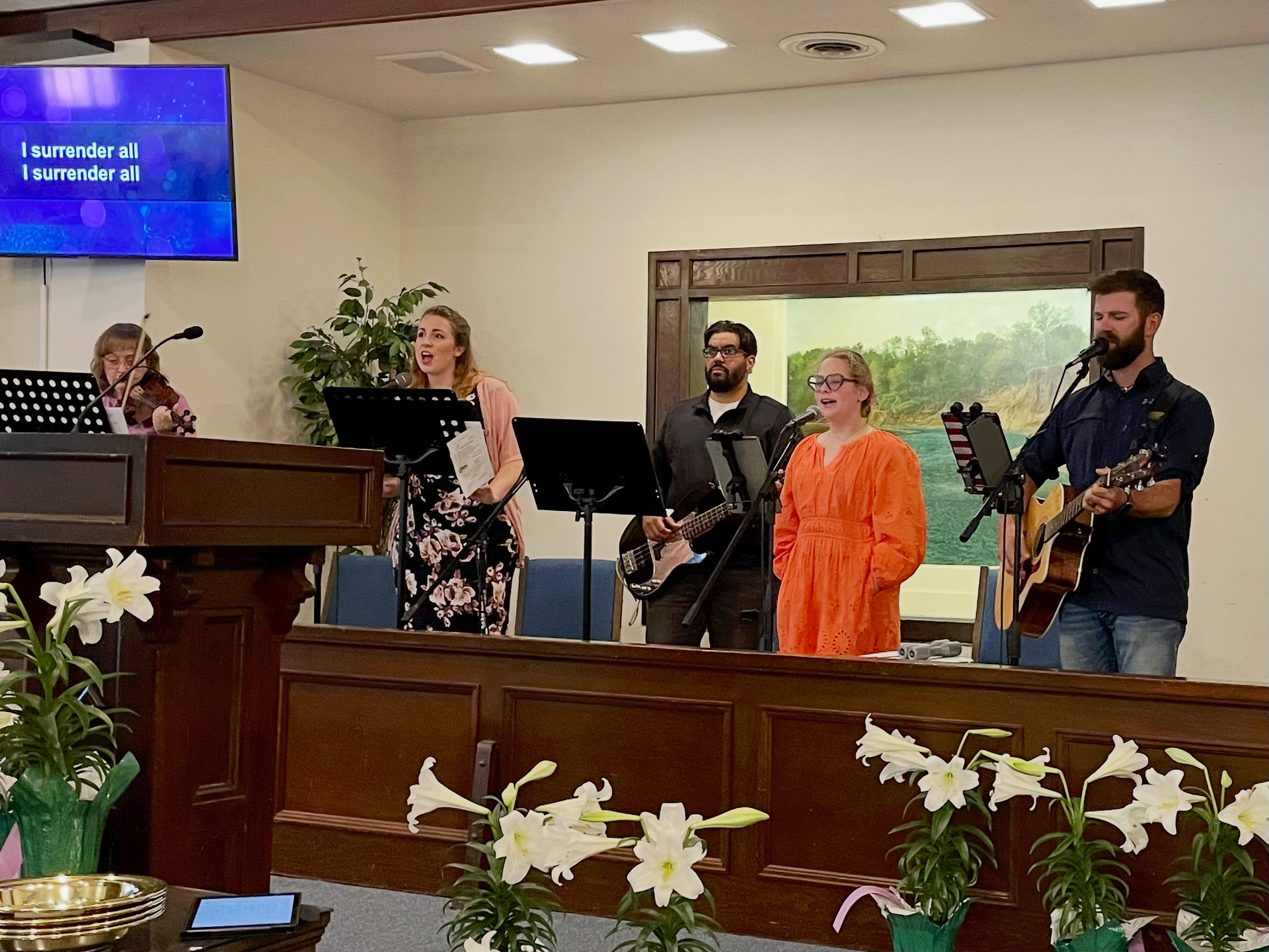 Worship band performing in a church. Musicians include a violinist, singers, and guitarists.