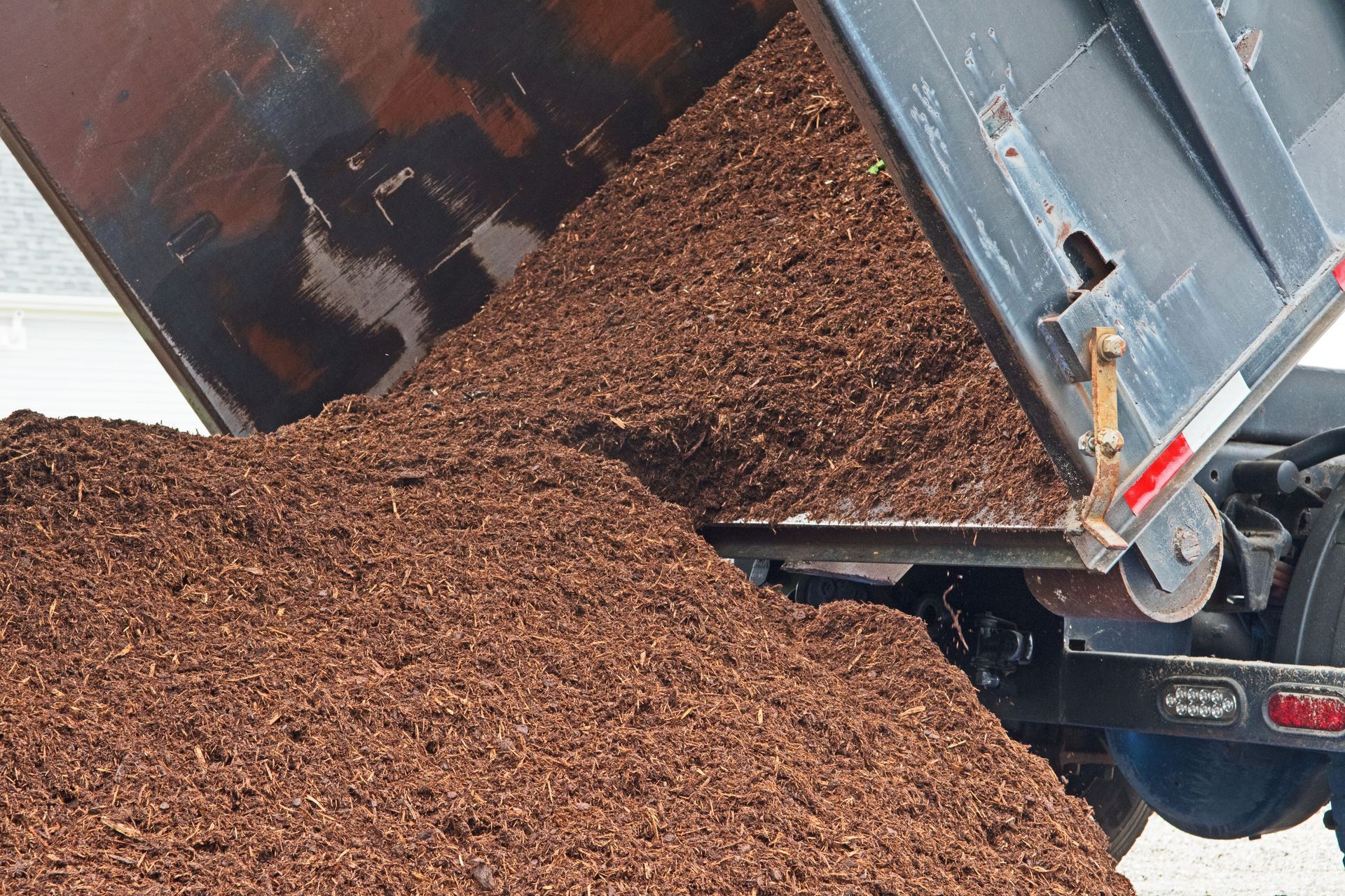 Dump truck unloading brown mulch.
