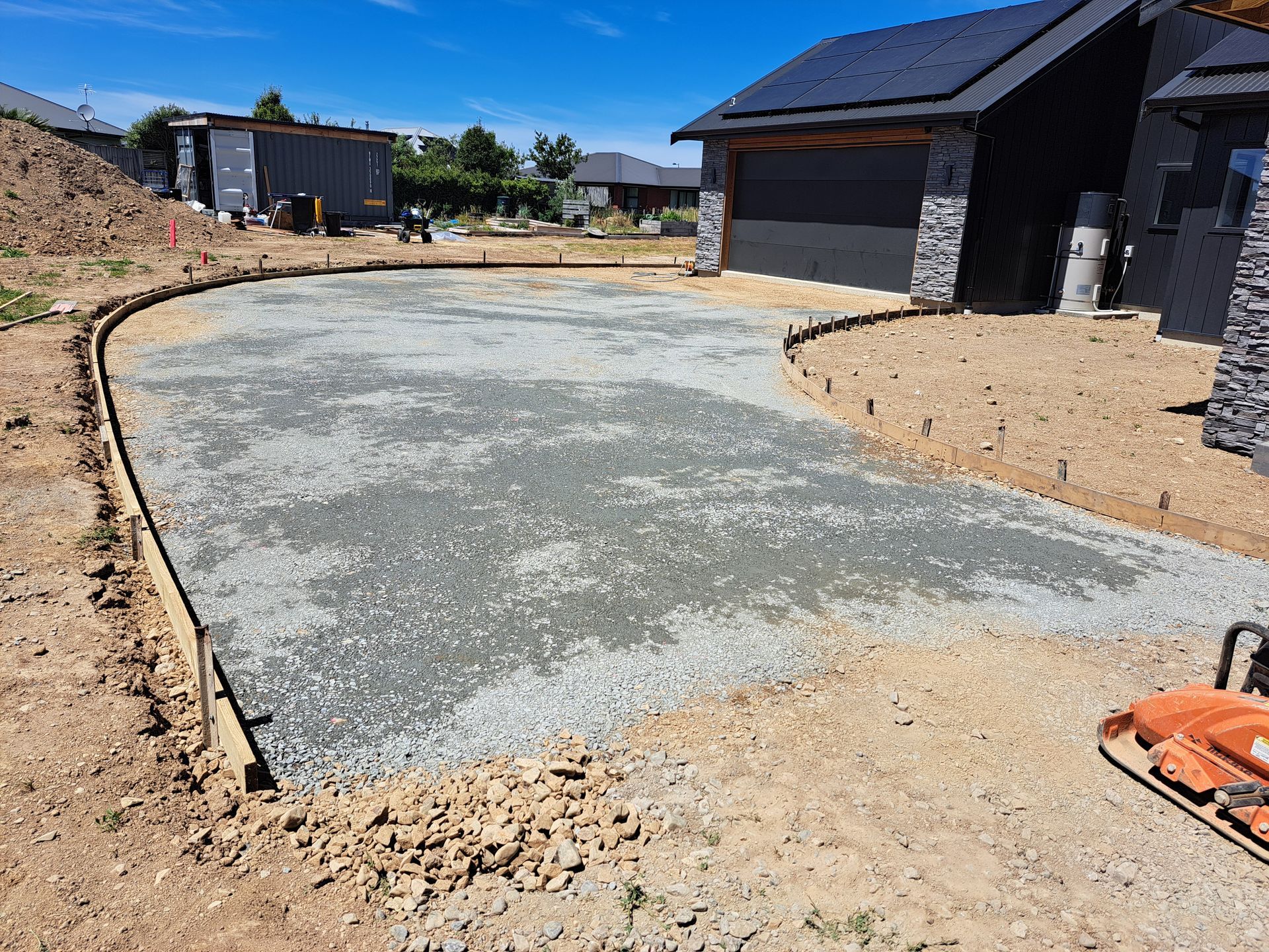 A residential driveway under construction with a leveled gravel base contained by wooden form boards in front of a house. A residential driveway under construction with a leveled gravel base contained by wooden form boards in front of a house.