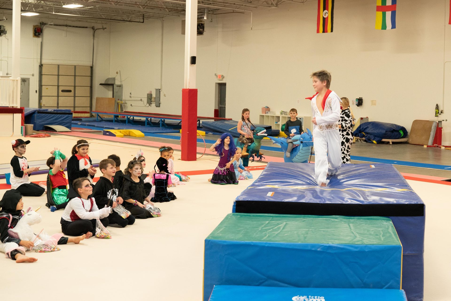 Parents night out Halloween party, gymnast dressed as Elvis crosses the mat stage