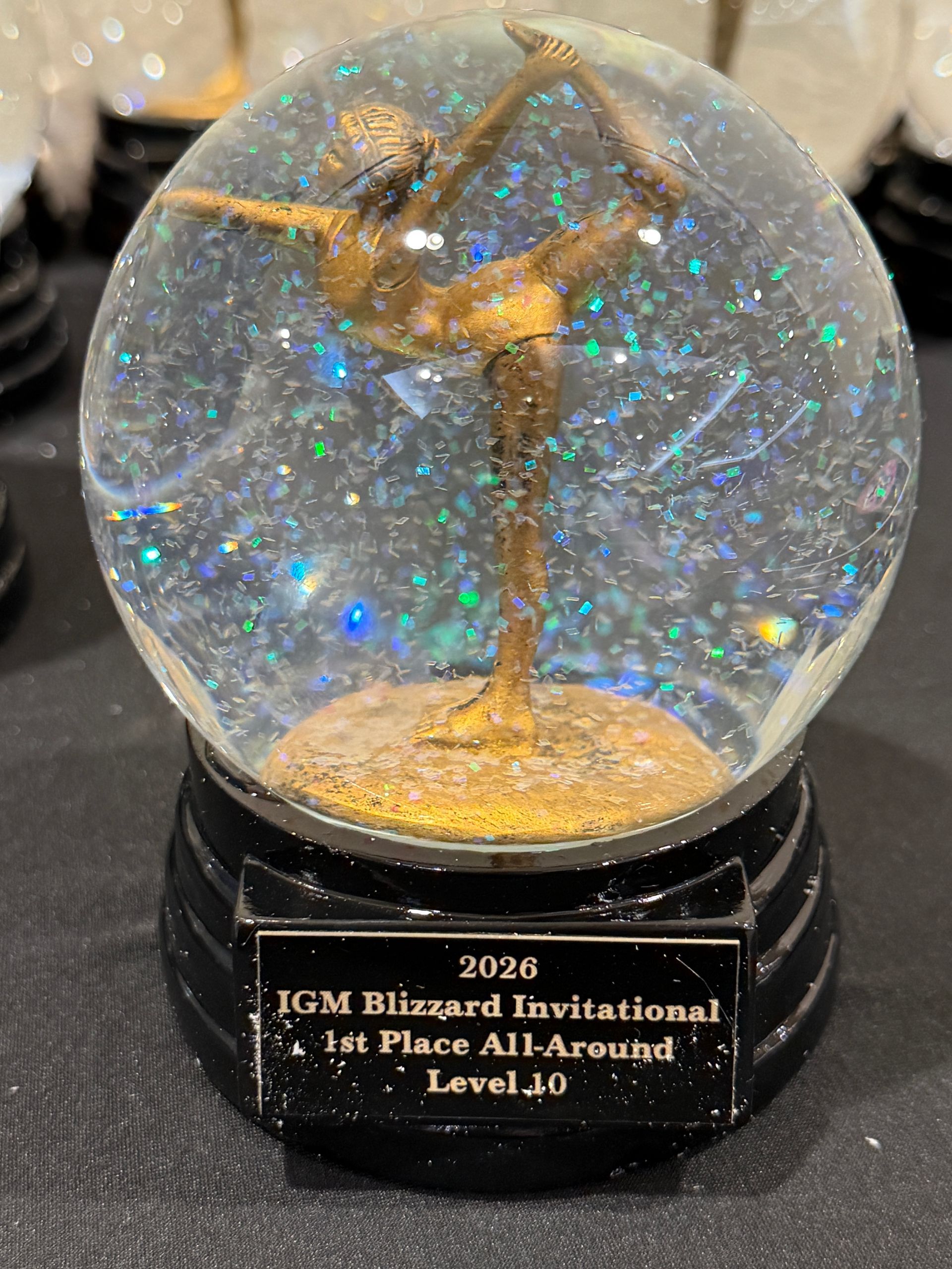 2026 JGM Blizzard Invitational First Place All-Around Team trophy with gold figure in a glittery snow globe base
