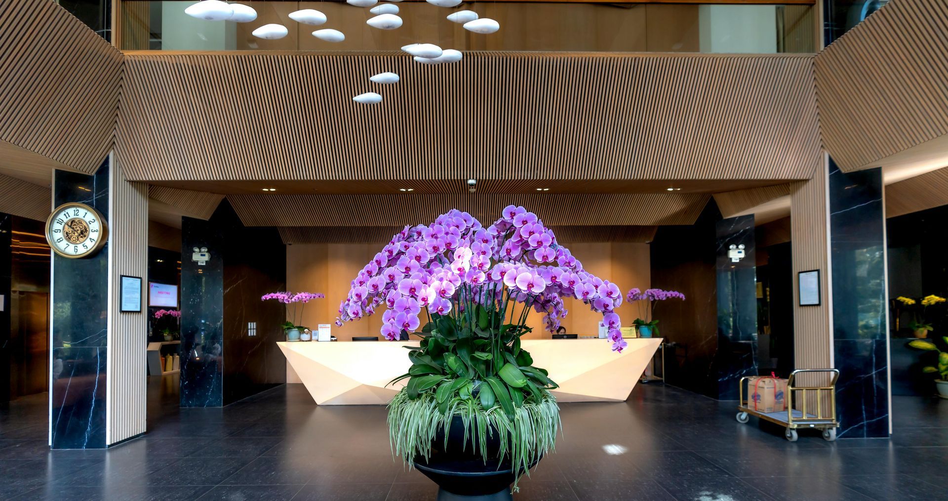 A large vase of purple flowers is in the lobby of a hotel.