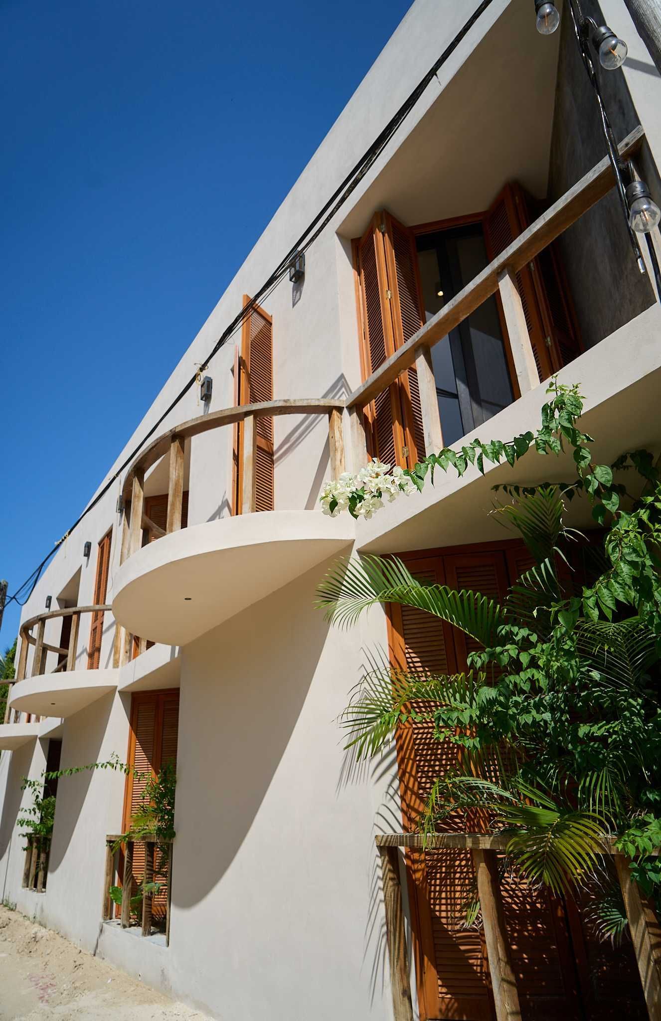 **Arquitectura tropical con balcones curvos, detalles de madera y exuberante vegetación.