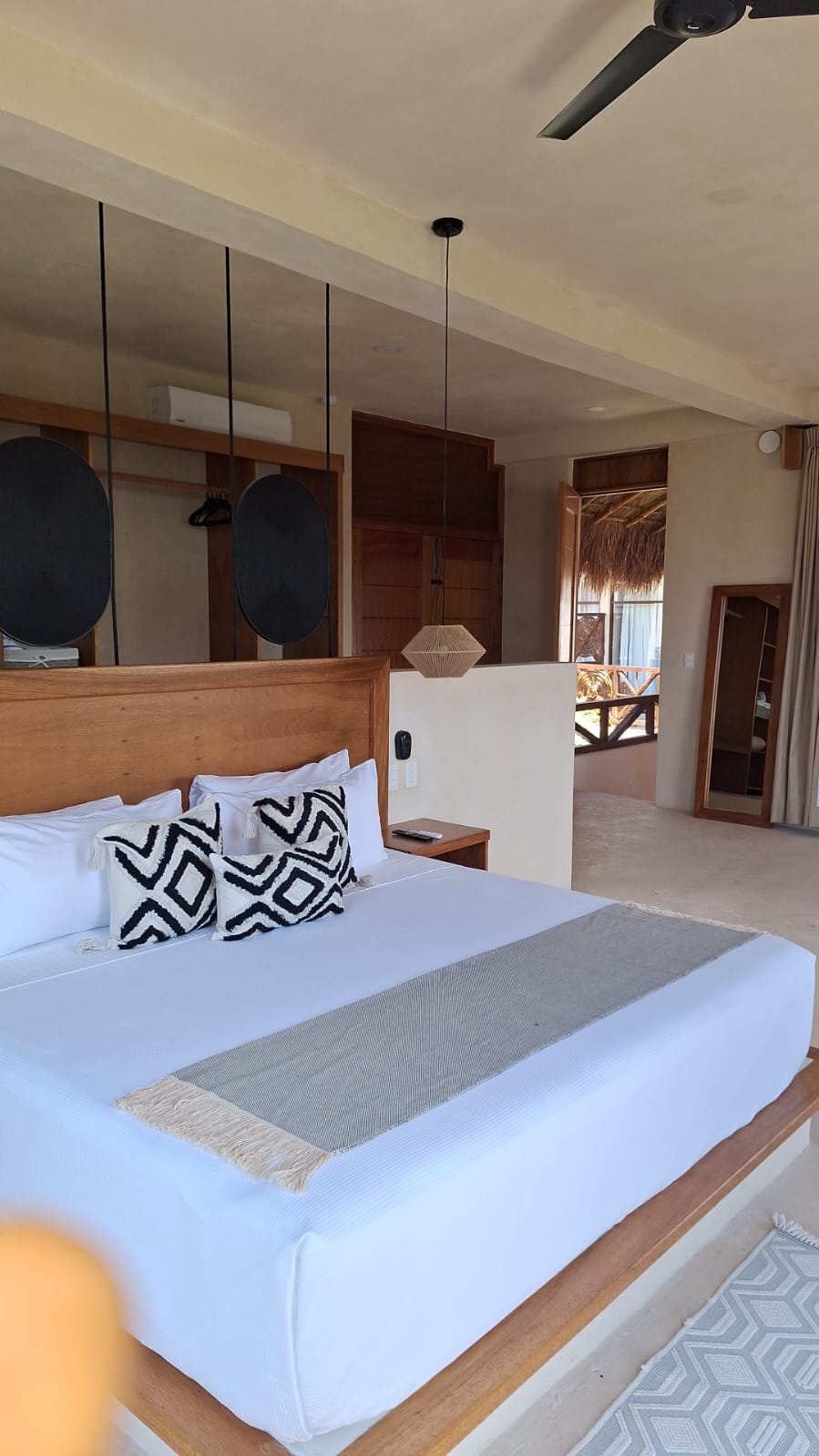Dormitorio moderno con una cama bien hecha, cabecero de madera, cojines estampados y estanterías abiertas.