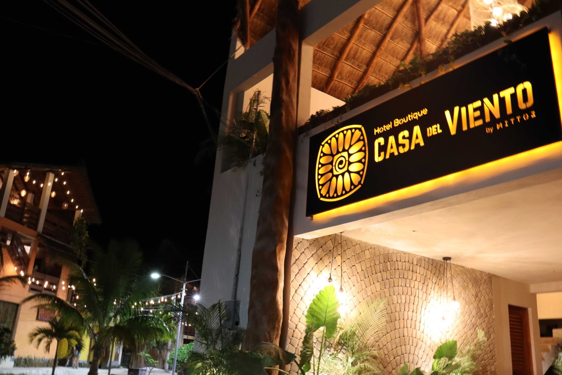 Exterior nocturno del restaurante Casa Viento, con el letrero iluminado en la entrada de un edificio.