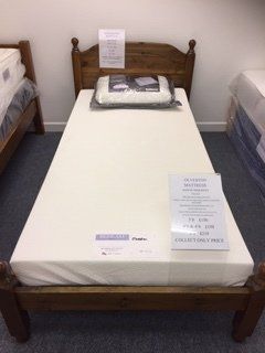 A single bed with a white mattress and a wooden headboard