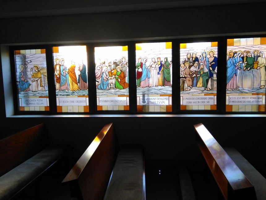 Persona ensamblando vidrieras de colores en un banco de trabajo de madera en un taller.