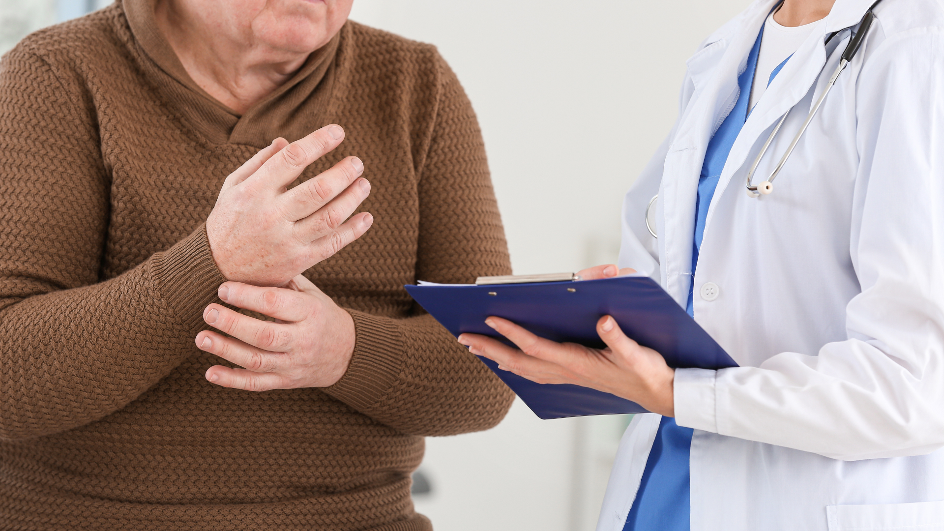 Patient with wrist pain consults doctor in a white coat, holding a clipboard.