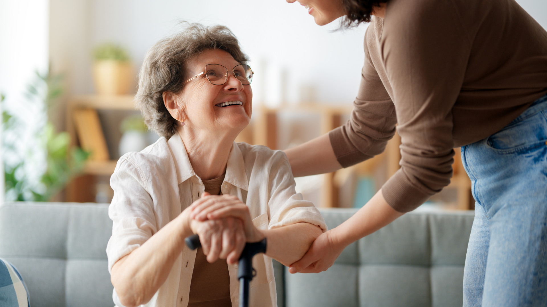 Woman smiles while another woman helps her, indoors.
