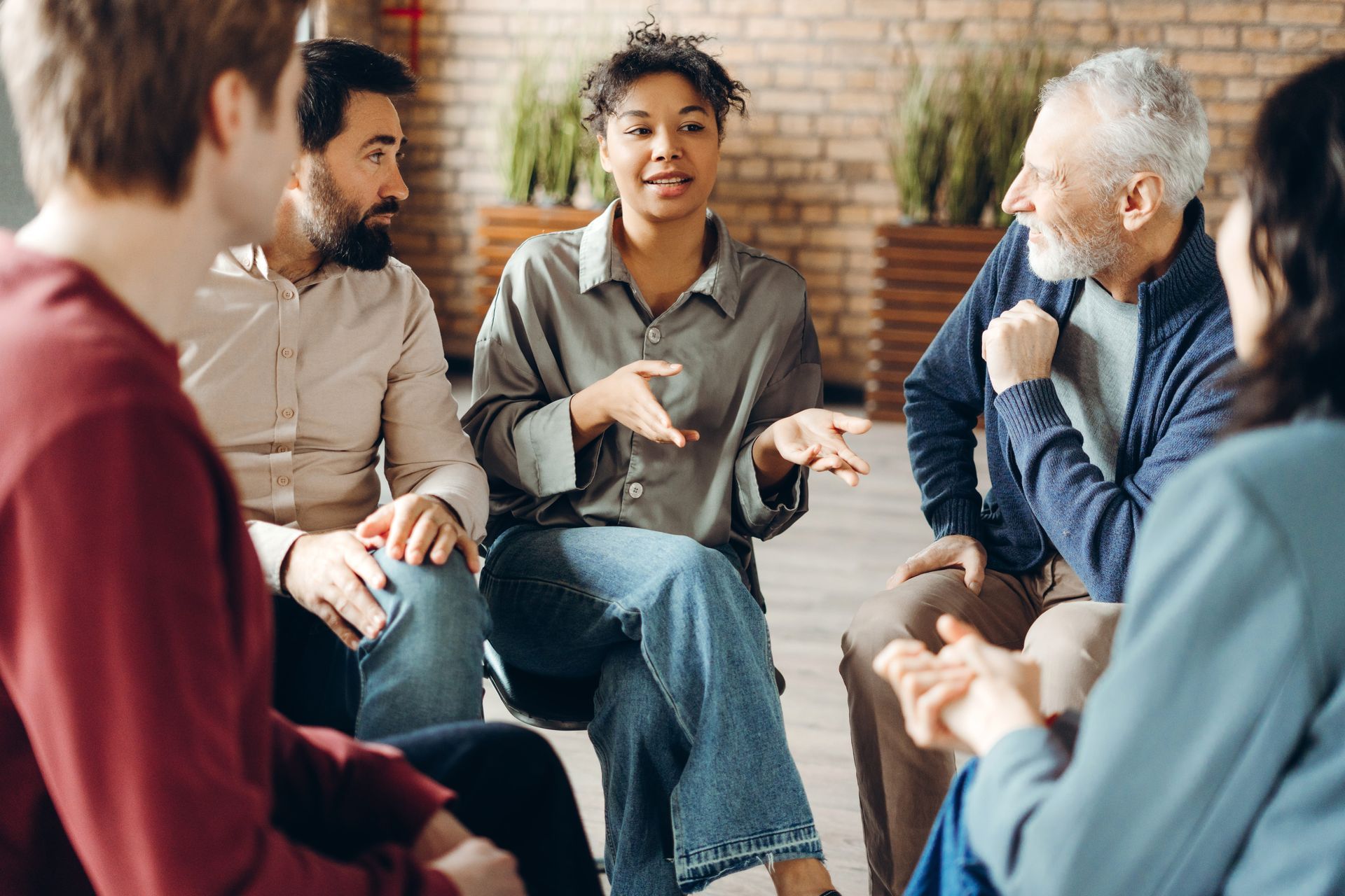 A family caregiver sits in a support group circle with others, representing caregiver burnout 